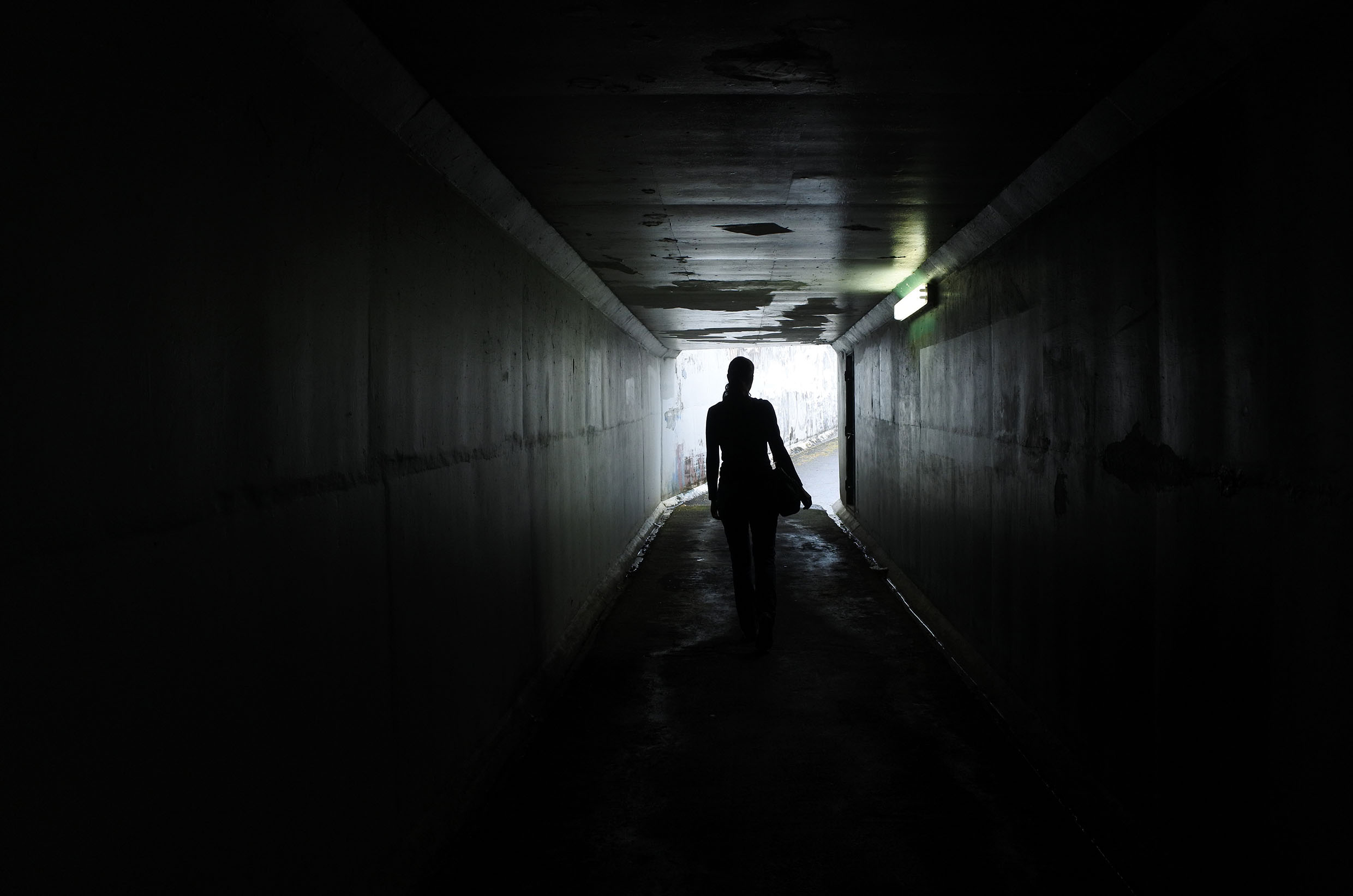silhouette of women in dark underpass